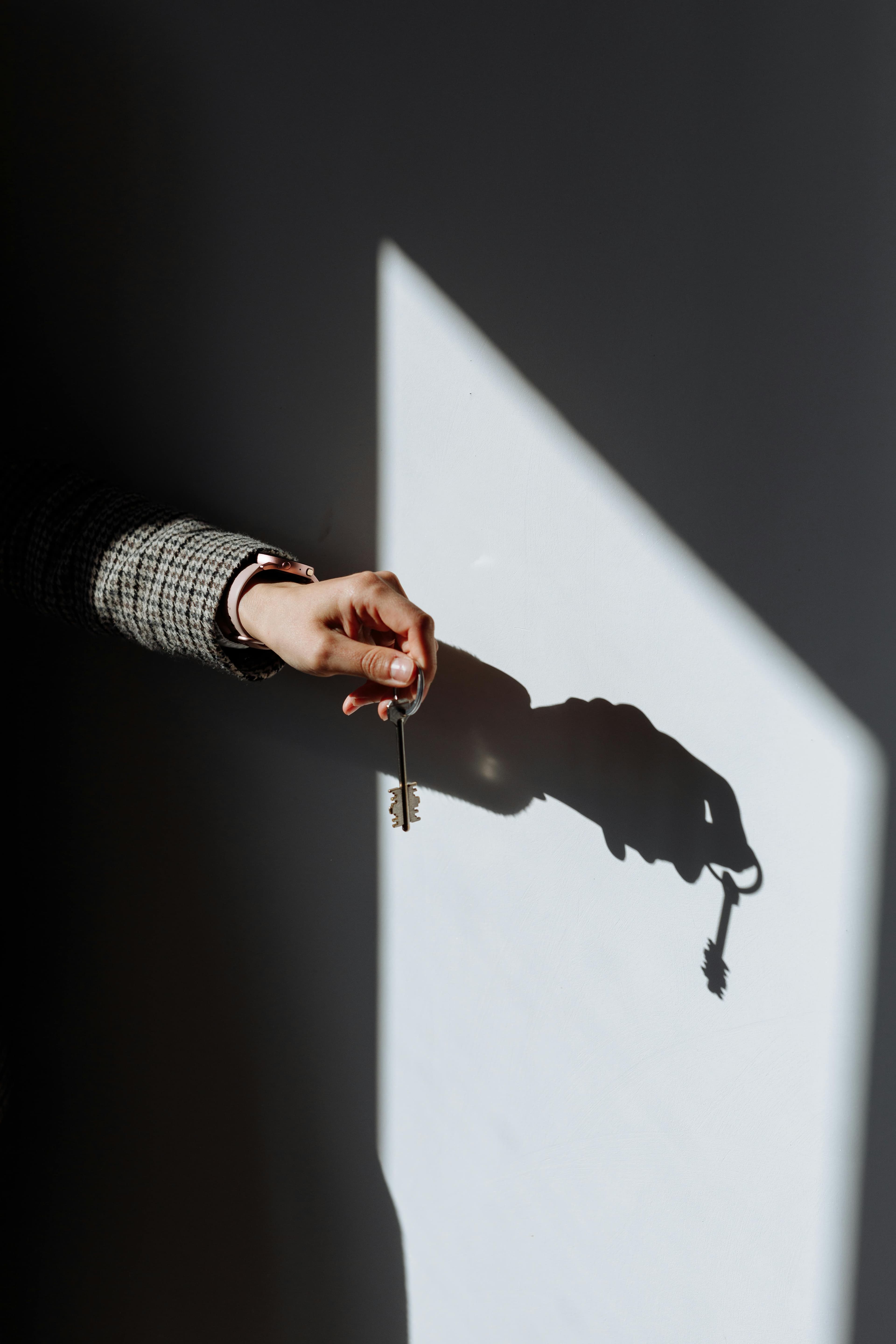 A hand reaches through a hole in a wall, casting shadows on the surfaces around it.